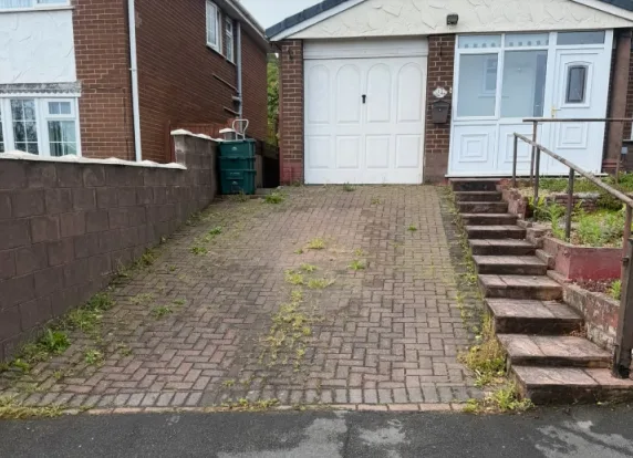 Block paving driveway before cleaning, covered in moss and weeds